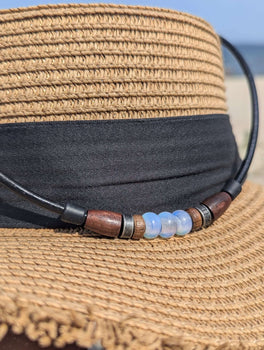 A Sundberg leather necklace with opalite beads drapes over the brim of a straw sunhat.