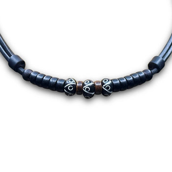 Necklace with three carved black beads and coconut spacer beads on black leather cord.