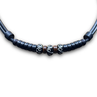 Necklace with three carved black beads and coconut spacer beads on black leather cord.